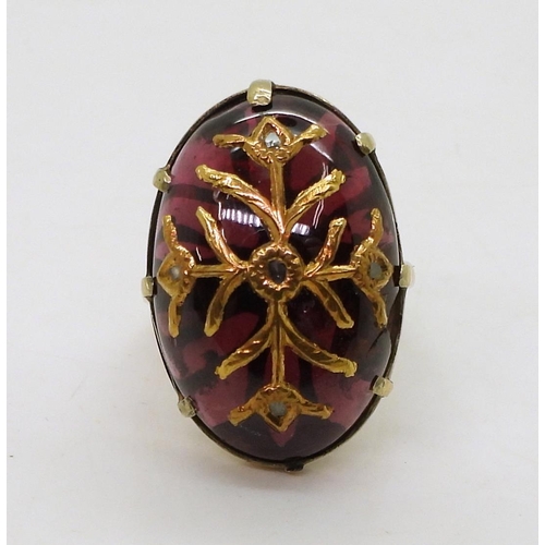 766 - A yellow metal ring set with an earlier garnet carbuncle with inset gold foliage with rose cut diamo... 