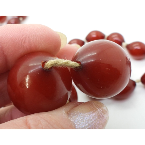 887 - Two strings of cherry amber coloured beads, weight 158.1gms