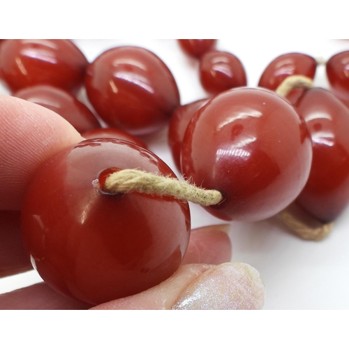 887 - Two strings of cherry amber coloured beads, weight 158.1gms