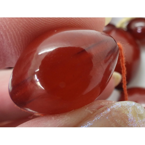 887 - Two strings of cherry amber coloured beads, weight 158.1gms