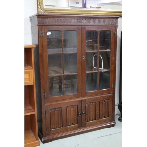 92 - A 20th century stained oak glazed bookcase with pair of glazed doors over pair of linenfold patterne... 