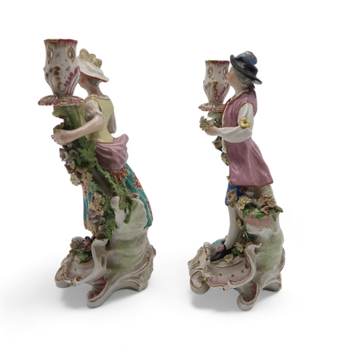 2252 - A PAIR OF DERBY PORCELAIN FIGURAL CANDLESTICKSmodelled as a woman with a floral dress holding flower... 