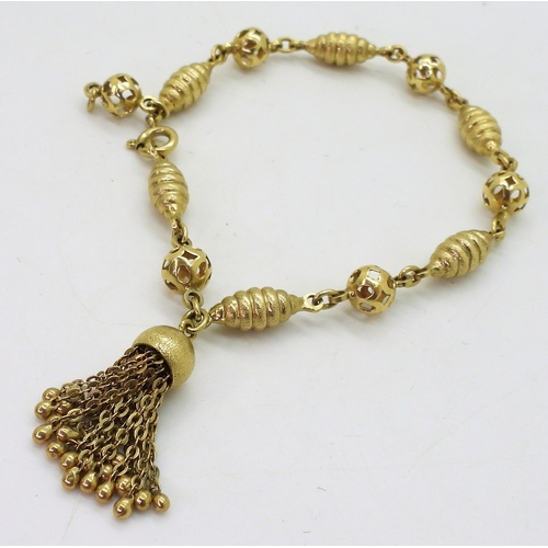 2819 - AN 18CT FANCY BEAD BRACELETwith alternate twist and pierced beads, with a tassel detail, stamped 750... 