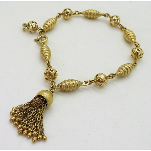 2819 - AN 18CT FANCY BEAD BRACELETwith alternate twist and pierced beads, with a tassel detail, stamped 750... 