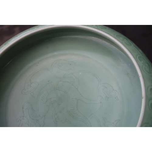 2405 - A CHINESE CELADON BOWLthe inner carved with a dragon and the outer carved with a ruyi band above mea... 