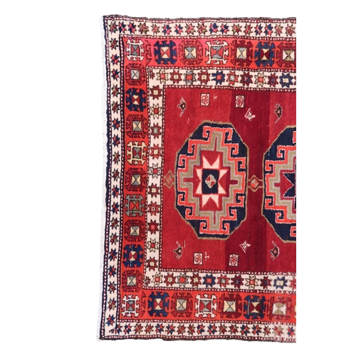 2122 - A RED GROUND CAUCASIAN RUNNER with five octagonal geometric medallions within orange and cream ... 