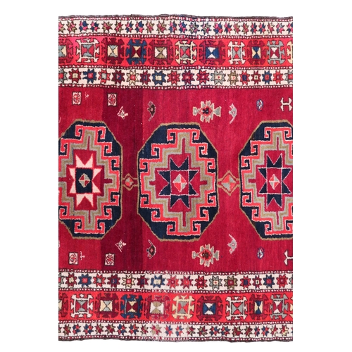 2122 - A RED GROUND CAUCASIAN RUNNER with five octagonal geometric medallions within orange and cream ... 