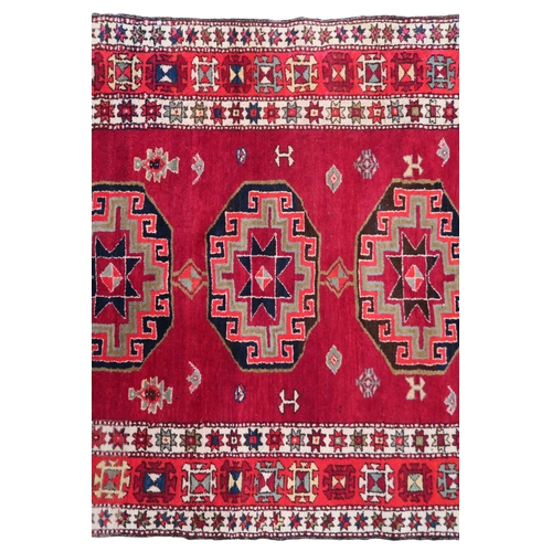 2122 - A RED GROUND CAUCASIAN RUNNER with five octagonal geometric medallions within orange and cream ... 