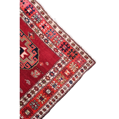 2122 - A RED GROUND CAUCASIAN RUNNER with five octagonal geometric medallions within orange and cream ... 