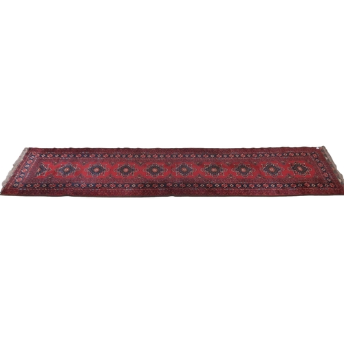 2125 - A RED GROUND FINE AFGHAN RUNNER with multiple dark medallions with multicoloured geometric bord... 