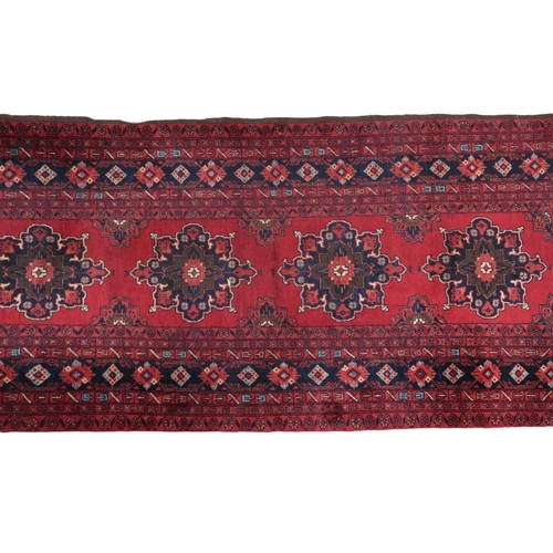 2125 - A RED GROUND FINE AFGHAN RUNNER with multiple dark medallions with multicoloured geometric bord... 