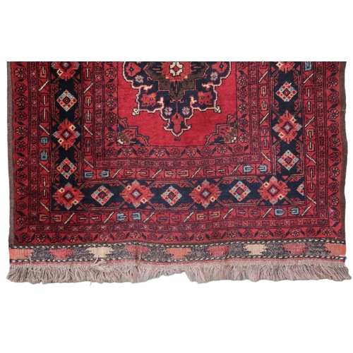 2125 - A RED GROUND FINE AFGHAN RUNNER with multiple dark medallions with multicoloured geometric bord... 