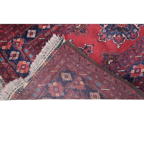 2125 - A RED GROUND FINE AFGHAN RUNNER with multiple dark medallions with multicoloured geometric bord... 