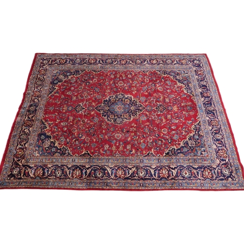 2126 - A LARGE RED GROUND TRADITIONAL PERSIAN MASHED RUG with light & dark blue central medallion ... 