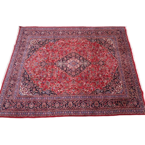 2130 - A RICH RED GROUND PERSIAN KASHAN RUG with dark blue floral patterned central medallion and matc... 