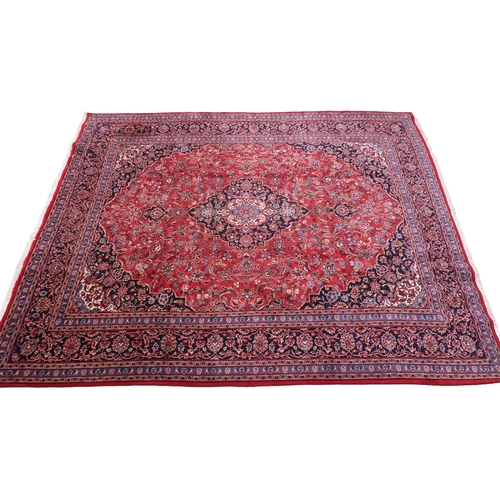 2130 - A RICH RED GROUND PERSIAN KASHAN RUG with dark blue floral patterned central medallion and matc... 