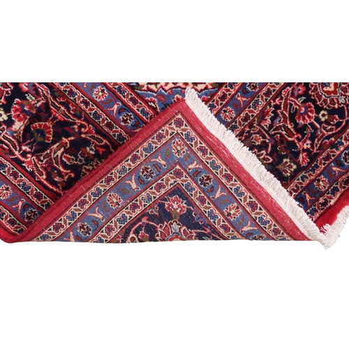 2130 - A RICH RED GROUND PERSIAN KASHAN RUG with dark blue floral patterned central medallion and matc... 