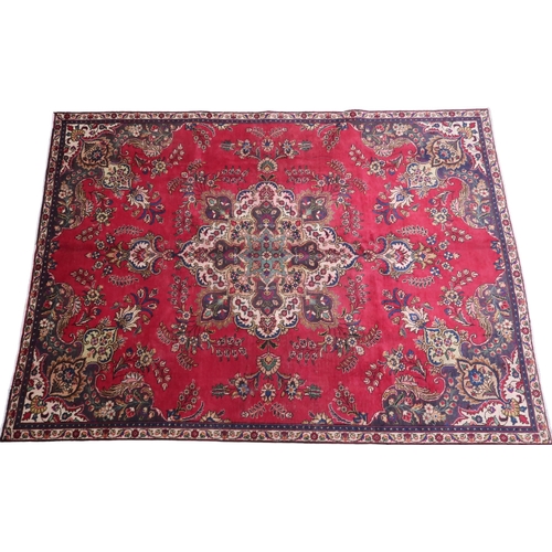 2131 - A RICH RED GROUND PERSIAN CARPET with multicoloured central medallion and spandrels on ground d... 