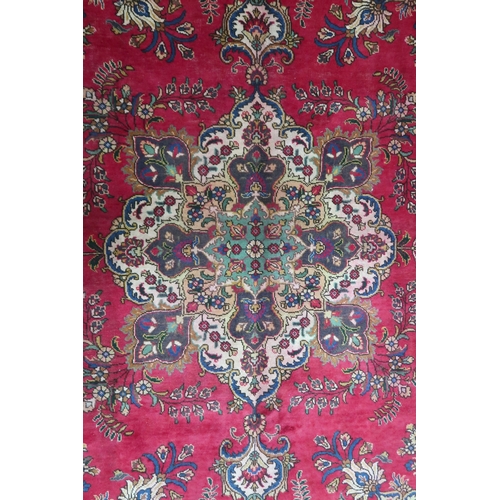 2131 - A RICH RED GROUND PERSIAN CARPET with multicoloured central medallion and spandrels on ground d... 