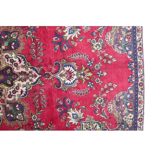 2131 - A RICH RED GROUND PERSIAN CARPET with multicoloured central medallion and spandrels on ground d... 