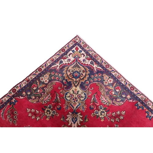 2131 - A RICH RED GROUND PERSIAN CARPET with multicoloured central medallion and spandrels on ground d... 