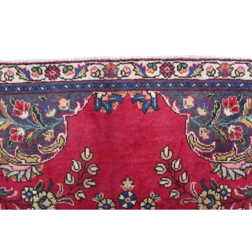 2131 - A RICH RED GROUND PERSIAN CARPET with multicoloured central medallion and spandrels on ground d... 