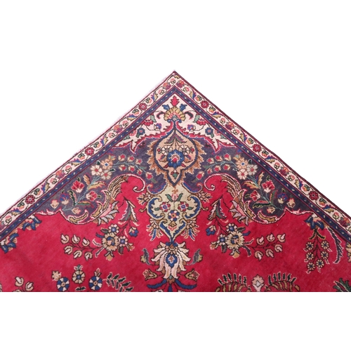 2131 - A RICH RED GROUND PERSIAN CARPET with multicoloured central medallion and spandrels on ground d... 