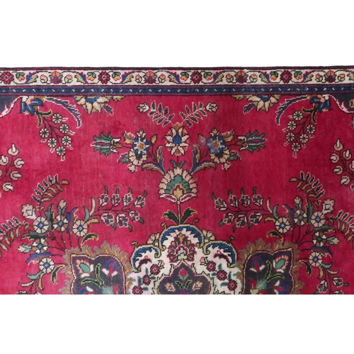 2131 - A RICH RED GROUND PERSIAN CARPET with multicoloured central medallion and spandrels on ground d... 