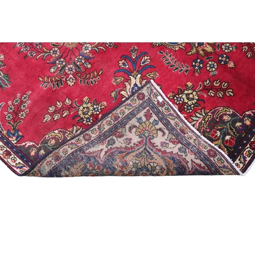 2131 - A RICH RED GROUND PERSIAN CARPET with multicoloured central medallion and spandrels on ground d... 