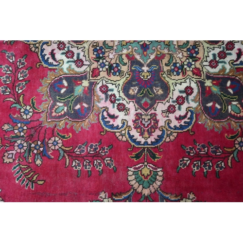 2131 - A RICH RED GROUND PERSIAN CARPET with multicoloured central medallion and spandrels on ground d... 