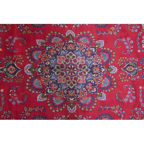 2132 - A RICH RED GROUND PERSIAN RUG with multicoloured sunburst central medallion and matching spandr... 