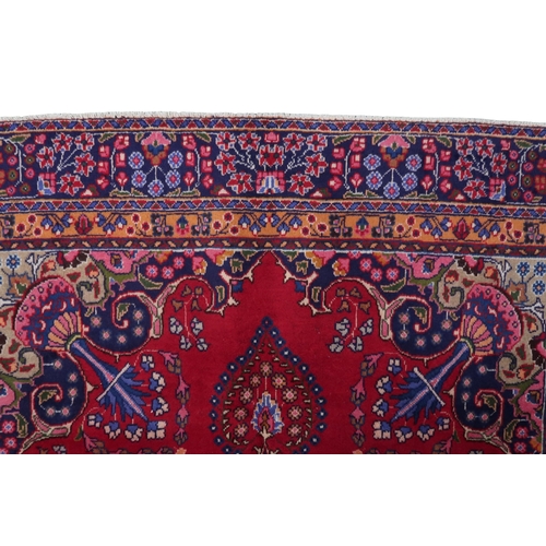 2132 - A RICH RED GROUND PERSIAN RUG with multicoloured sunburst central medallion and matching spandr... 