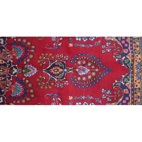 2132 - A RICH RED GROUND PERSIAN RUG with multicoloured sunburst central medallion and matching spandr... 