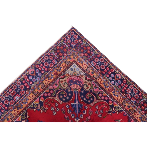 2132 - A RICH RED GROUND PERSIAN RUG with multicoloured sunburst central medallion and matching spandr... 