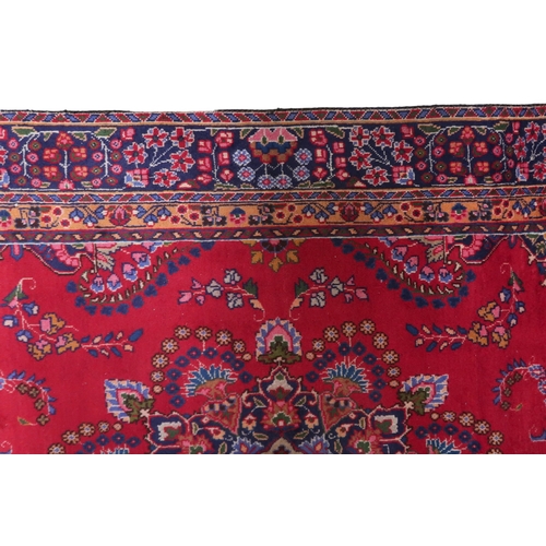 2132 - A RICH RED GROUND PERSIAN RUG with multicoloured sunburst central medallion and matching spandr... 