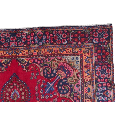 2132 - A RICH RED GROUND PERSIAN RUG with multicoloured sunburst central medallion and matching spandr... 