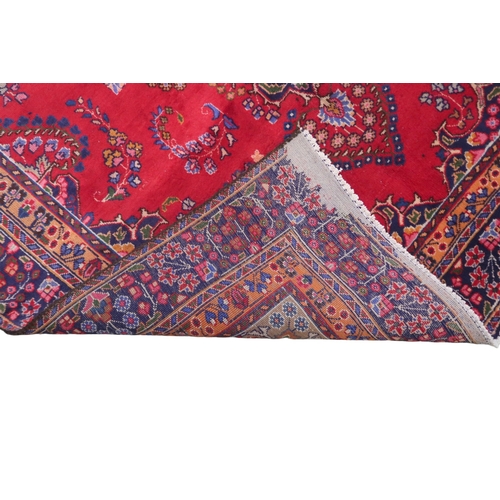 2132 - A RICH RED GROUND PERSIAN RUG with multicoloured sunburst central medallion and matching spandr... 