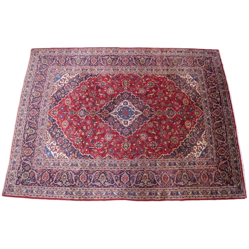 2133 - A RED GROUND IRANIAN TRADITIONAL KASHAN CARPET with dark blue and cream diamond central medalli... 