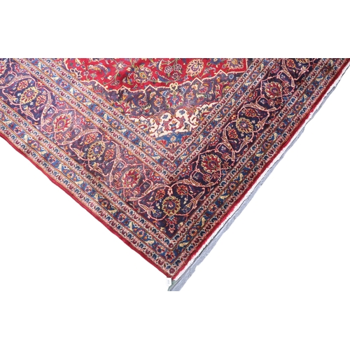 2133 - A RED GROUND IRANIAN TRADITIONAL KASHAN CARPET with dark blue and cream diamond central medalli... 