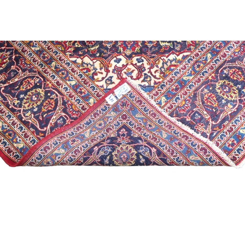 2133 - A RED GROUND IRANIAN TRADITIONAL KASHAN CARPET with dark blue and cream diamond central medalli... 