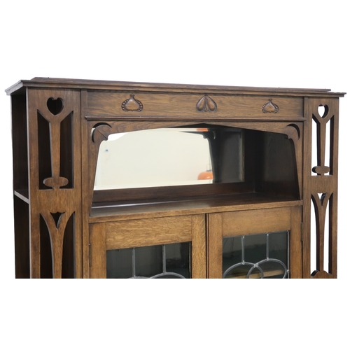 2024 - AN OAK ARTS & CRAFTS LEADED GLASS BOOKCASE IN THE MANNER OF E A TAYLORwith top frieze carved wit... 