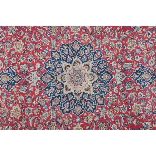 2134 - A RED GROUND TABRIZ RUG with dark blue and ivory sunburst central medallion and light blue and ... 