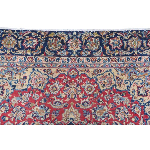 2134 - A RED GROUND TABRIZ RUG with dark blue and ivory sunburst central medallion and light blue and ... 