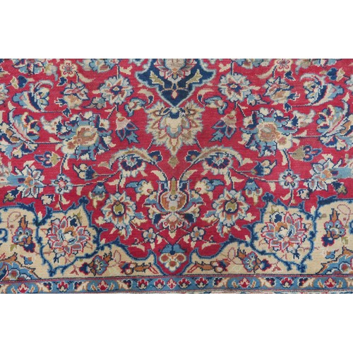 2134 - A RED GROUND TABRIZ RUG with dark blue and ivory sunburst central medallion and light blue and ... 