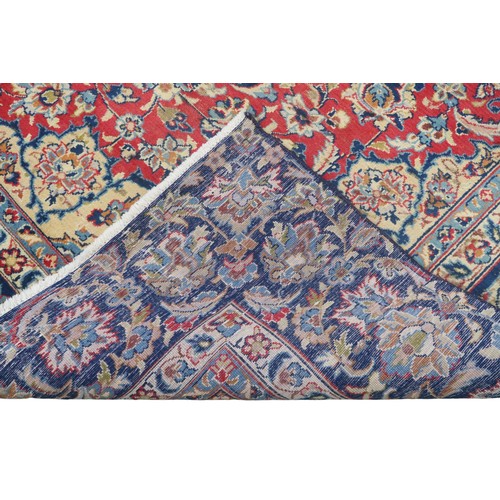 2134 - A RED GROUND TABRIZ RUG with dark blue and ivory sunburst central medallion and light blue and ... 