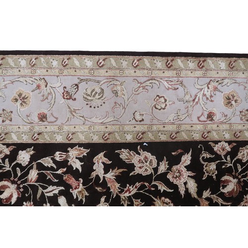 2121 - A LARGE DARK GROUND INDIAN WOOL ZEIGLER STYLE RUG with floral/foliate patterned ground within beige ... 