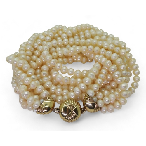 2820 - MULTI STRAND PEARLSwith a fancy fan patterned yellow and white 9ct gold box clasp, the cream freshwa... 