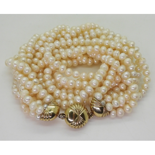 2820 - MULTI STRAND PEARLSwith a fancy fan patterned yellow and white 9ct gold box clasp, the cream freshwa... 