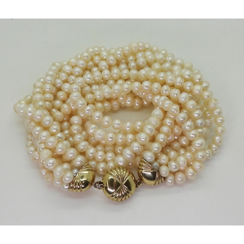 2820 - MULTI STRAND PEARLSwith a fancy fan patterned yellow and white 9ct gold box clasp, the cream freshwa... 