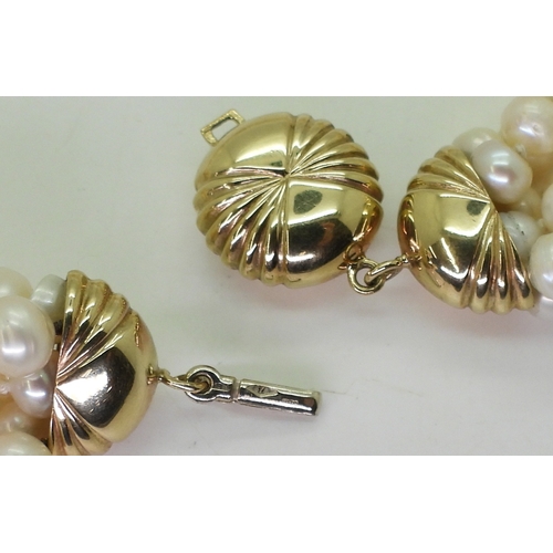 2820 - MULTI STRAND PEARLSwith a fancy fan patterned yellow and white 9ct gold box clasp, the cream freshwa... 